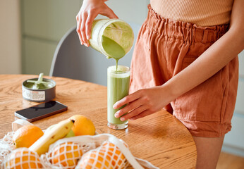 Closeup of a female pouring green healthy smoothie to detox, drinking vitamins and nutrients. Woman nutritionist having a fresh fruit juice to cleanse and provide energy for healthy lifestyle