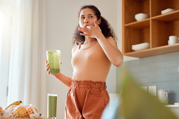 Eating, tasting and drinking a green health smoothie with a young female in a kitchen. Woman on a...