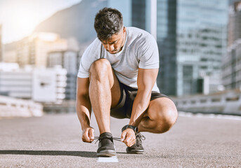 Wellness and fitness runner ties shoes lace before running in a city street during summer. Healthy...
