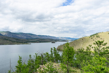 Lake, mountains, clouds, summer. A picturesque panoramic landscape over the lake, shot day after day with clouds in the sky.  Landscape of a summer day on the lake. 