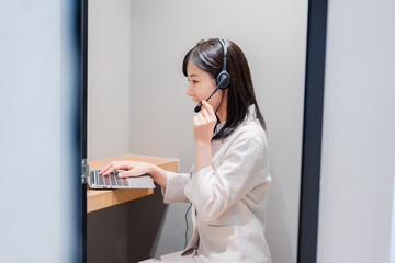 シェアオフィスの個室ブースでリモート会議をする女性