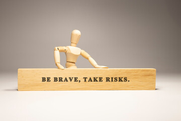 Be brave, take risk. written on wooden surface. Personal development and education