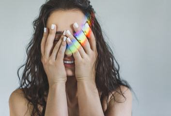 Portrait of a young woman covering her eyes with her palms and laughing with the reflection of a...