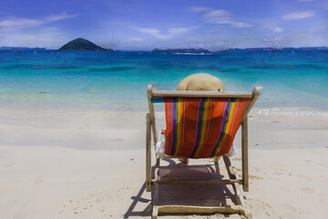 woman wearing sun hat lay down on deck chair on the beach on sunny day,relax vacation holliday long weekend concept