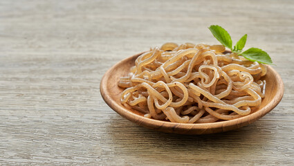 concept of salad brown konjac noodle and green leaves in wooden plate on white table background                                                                                      