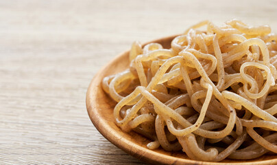 close up concept of salad brown konjac noodle in wooden plate on white table background                                                                                     