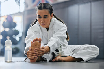 . Female karate school student doing a warmup, stretch or exercise with serious, determine and...