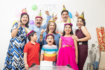Cheerful indian asian generational family celebrate indoor birthday party.