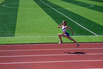 Fototapeta premium Young caucasian woman is engaged in jogging at the stadium outdoors.