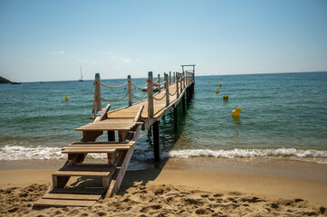 Wooden pier for guests and yachts on legendary Pampelonne beach near Saint-Tropez, summer vacation on white sandy beaches of French Riviera, France
