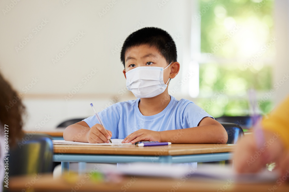 Poster . Face mask to protect from covid during pandemic, creative school student learning in class and writing in notebook in classroom. Boy sitting at a desk, doing education task and studying with books.