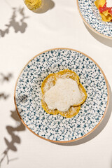 Italian ravioli with cheese and creamy sauce in ceramic plate on white table sunny day. Cheese ravioli with creamy espuma and parmesan. Italian ravioli with quattro formaggi filled and creamy