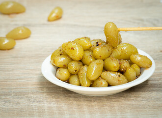 Pickled grapes in a white dish, with a sour taste, paired with a chilli, salt and sugar dipping...