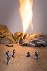 Miniature firefighters at a car accident scene in flames