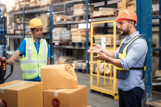 Supervisor, manager or boss to angry, scold or mad to worker, employee inside distribution warehouse about bad, damage, broken or dented of cardboard box package. May called carton, parcel, cargo.
