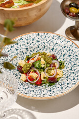 Traditional italian food - panzanella salad with tomatoes, onion rings and croutons. Panzanella salad on white table in summer menu. Composition with Tomato salad and glasses in sunny day.