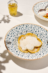 Italian ravioli with cheese and creamy sauce in ceramic plate on white table sunny day. Cheese ravioli with creamy espuma and parmesan. Italian ravioli with quattro formaggi filled and creamy