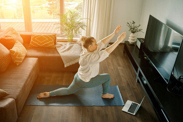 Woman doing online yoga at home. Female trener teaches asana in video conference. Health care, authenticity, sense of balance and calmness.	 - obrazy, fototapety, plakaty