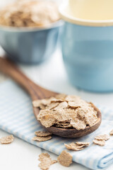 Whole grain cereal flakes. Wholegrain breakfast cereals in wooden spoon on kitchen table.