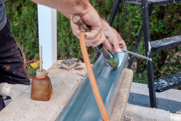 soldering a gutter with an old copper soldering iron. Closeup hand soldering zinc gutter roof....