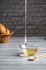 bee honey on a wooden white background, pour honey into a cup, a drop of honey, space for text, forest honey