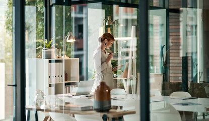 A modern office, building interior and a businesswoman doing online research on a tablet or looking...