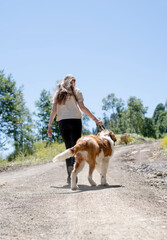 young woman holding St.Bernard dog hiking at the mountains