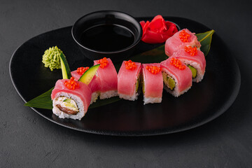 rolls with tuna and red caviar on a black plate