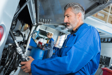 mature male mechanic working on bus in garage