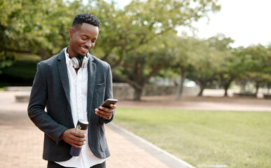Young, cool smiling businessman on a phone having a walk in the park outside in nature. Happy man texting, chatting or reading messages on a smartphone outdoors on a break from work, over copy space.