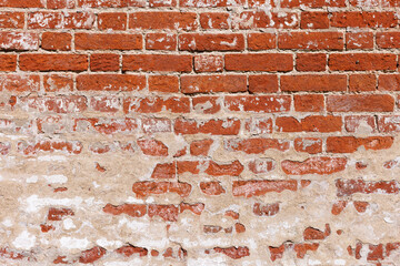 An old red brick wall with remnants of plaster.