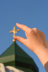 Christian church and children's hand with a cross.