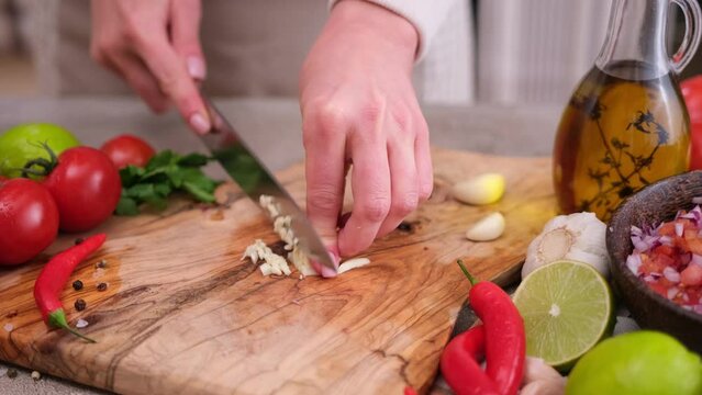 Woman slices garlic on a kitchen board using a knife