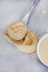 Pure sesame tahini with sesame seeds on mottled grey with copy space