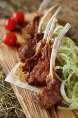 Fried ribs lie on a wooden board and hay. The concept of restaurant cuisine.