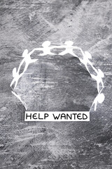 staff shortages and business struggling after the pandemic, peper people chain with Help Wanted text on gray background