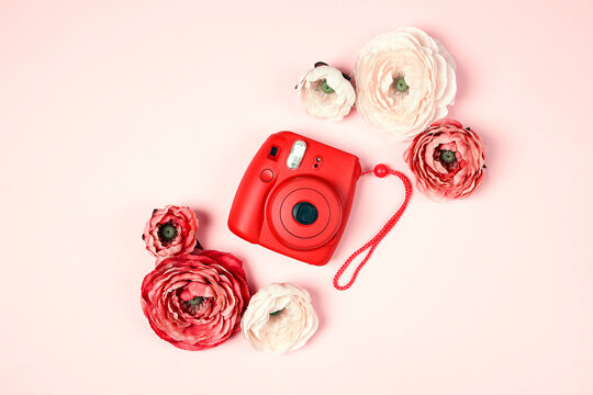 Modern instant camera with peony flowers on pastel  pink background.