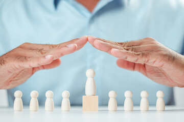 A man's hand protects a wooden peg doll that is like a corporate member. Risk and Crisis Prevention...