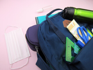      As COVID-19 prevention goes back to school and new normal concept. Top view of backpack with...