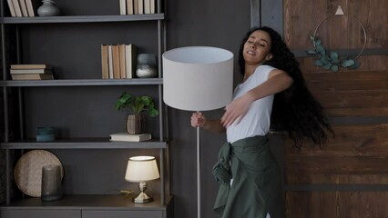 Young funny comical woman having fun dances waltz alone excited girl humorist dancing expressively hugs and kisses lamp fooling around moves energetically enjoying pleasant favorite music at home