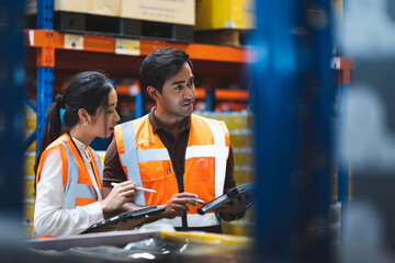 Warehouse worker and manager checks stock and inventory with using digital tablet computer in the retail warehouse full of shelves with goods. Working in logistics, Distribution center. - obrazy, fototapety, plakaty