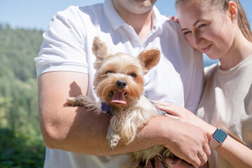 young couple travelling with yourshire terrier dog at the mountains,