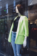 Female mannequin in stylish clothes in a shop window