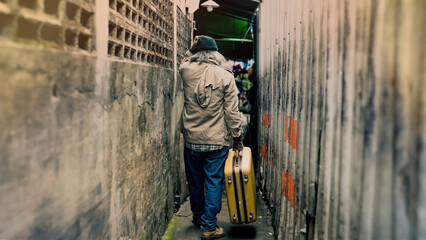  Taken from behind a homeless Asian man carrying a bag in a narrow alley looking for work and food from people to donate. An elderly man with no work, no home, had to live on the roadside.