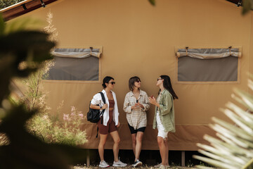Three nice young caucasian brunette women communicate relaxing on weekend in countryside. Girlfriends wear sunglasses, casual wear. Leisure lifestyle and beauty concept.
