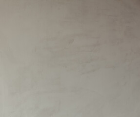 A plastered drywall surface with beige paint texture. Painted damaged white wall background.
