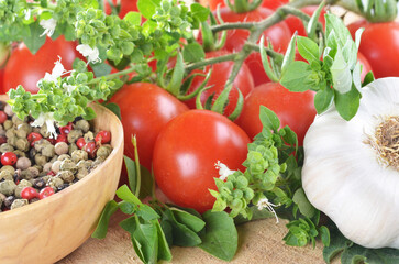Ripe cherry tomatoes, peppercorns, garlic, basil, on a wooden table close-up