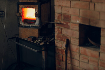 Blacksmith forge oven with hot flame. Smith heating iron piece of steel in fire of red-hot forge.