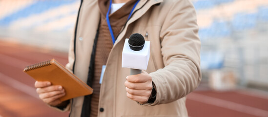 Male reporter with microphone at the stadium, closeup