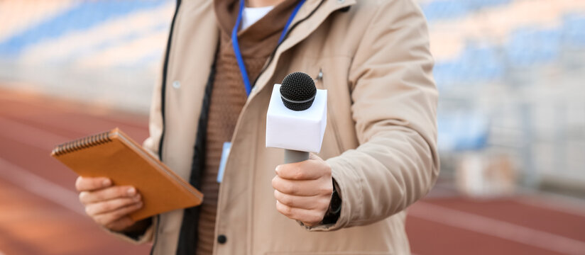 Male reporter with microphone at the stadium, closeup